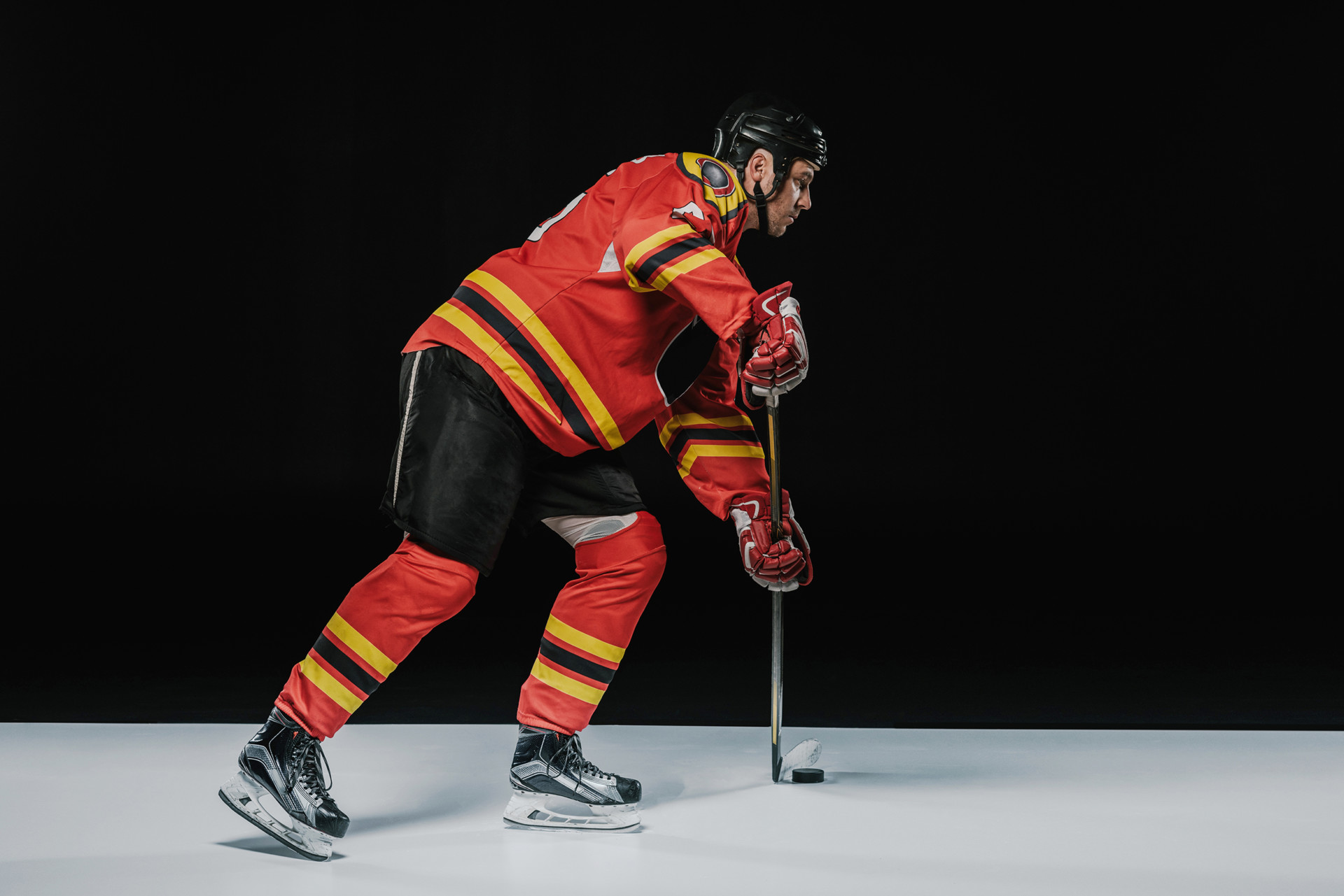 Side view of young professional sportsman playing ice hockey on